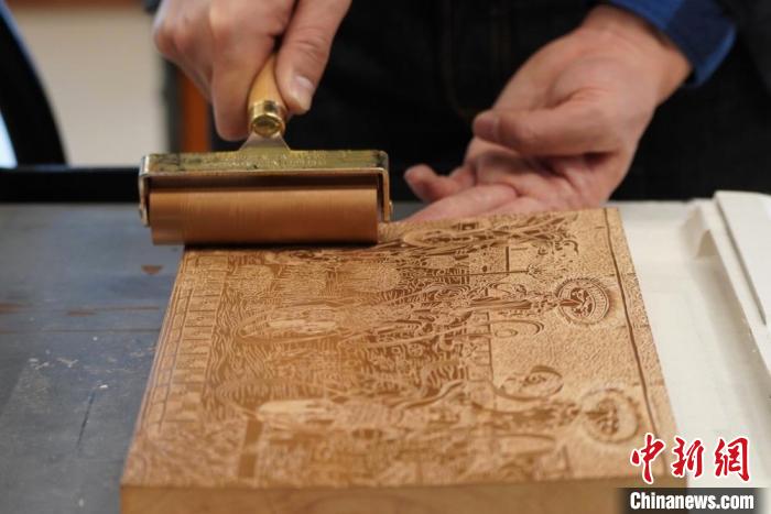 圖為徐晉林工作室工作人員正在給雕好壁畫的版面滾油墨?！【琶赖┰?　攝