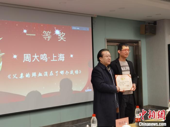 圖為作家、西北師范大學(xué)新聞與傳媒學(xué)院院長(zhǎng)徐兆壽頒發(fā)一等獎(jiǎng)證書，代領(lǐng)獎(jiǎng)?wù)呱吓_(tái)領(lǐng)獎(jiǎng)?！钅?攝