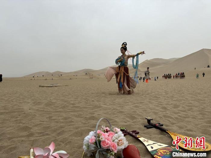 圖為2023年4月底，敦煌大漠“逐舞者”奧楠在鳴沙山月牙泉景區(qū)視頻直播敦煌舞?！●T志軍 攝