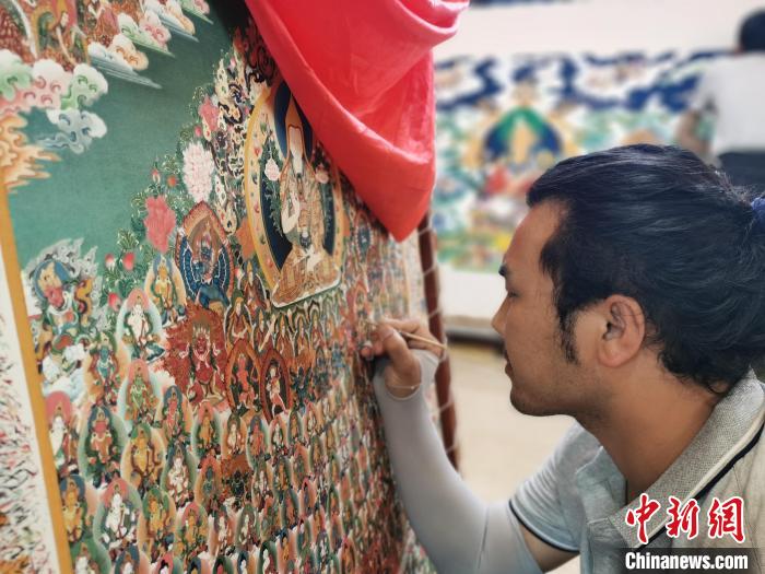 圖為更登才讓的徒弟繪畫唐卡?！?zhí)砀?攝