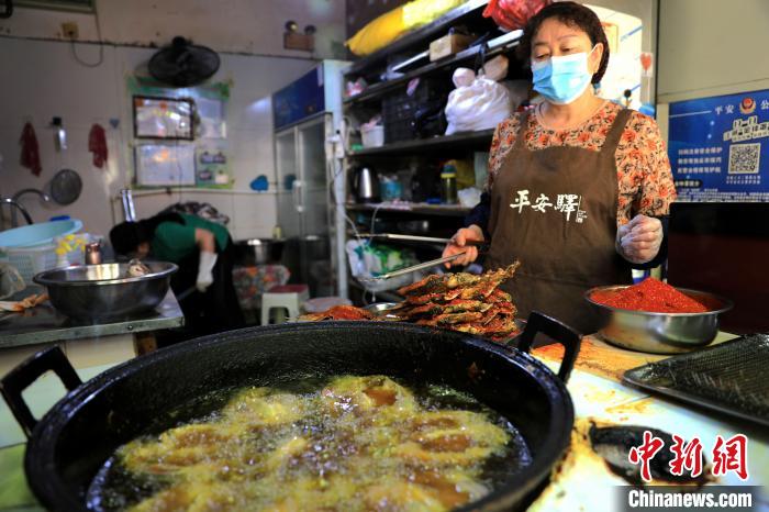 圖為平安驛·河湟民俗文化體驗地內的商戶炸干板魚?！⊙Φ?攝