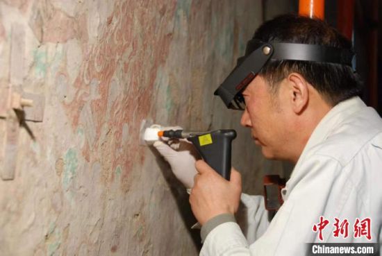 敦煌研究院研究員樊再軒進(jìn)行壁畫修復(fù)。(資料圖)張?jiān)莆?攝