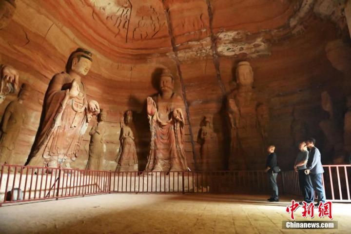 7月15日，游人參觀甘肅省平?jīng)鍪袥艽h百里石窟長廊中的南石窟寺1號窟。百里石窟長廊位于涇川縣境內(nèi)，由512個(gè)石窟、5眼窟中石井組成，現(xiàn)存王母宮石窟、鳳凰山石窟、南石窟寺、丈八寺石窟、羅漢洞石窟、太山寺石窟等規(guī)模較大的石窟群，還有數(shù)量眾多的小石窟群。南石窟寺開鑿于北魏永平三年，其中1號窟屬于大型七佛窟，七佛高達(dá)6米。中新社記者 李亞龍 攝